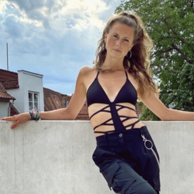 Tänzerin Hannah Bruns posiert lässig in einem knappen Top vor einer grauen Mauer in Lübeck